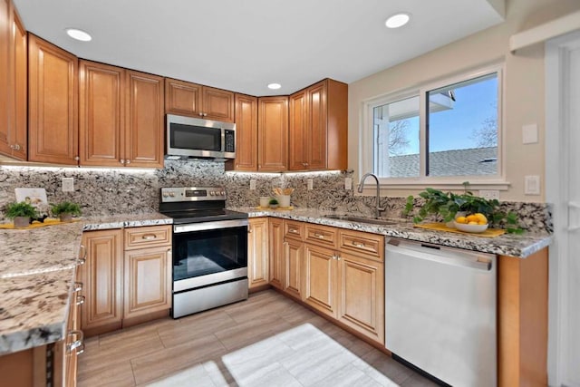 kitchen featuring light stone countertops, sink, backsplash, and stainless steel appliances