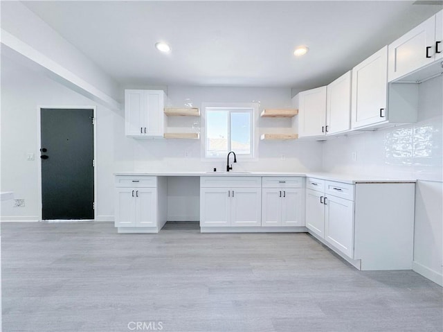 kitchen with white cabinets, light wood-type flooring, and sink