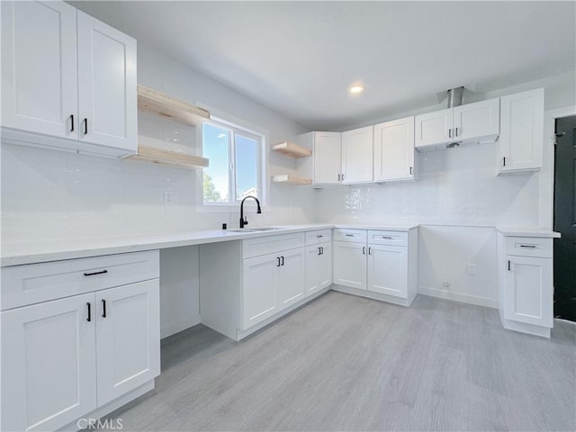 kitchen with sink, light hardwood / wood-style flooring, white cabinetry, and tasteful backsplash