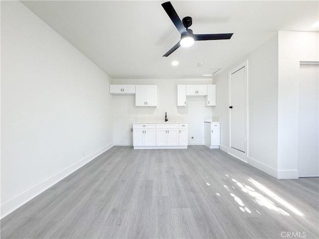 unfurnished living room featuring sink, ceiling fan, and light wood-type flooring