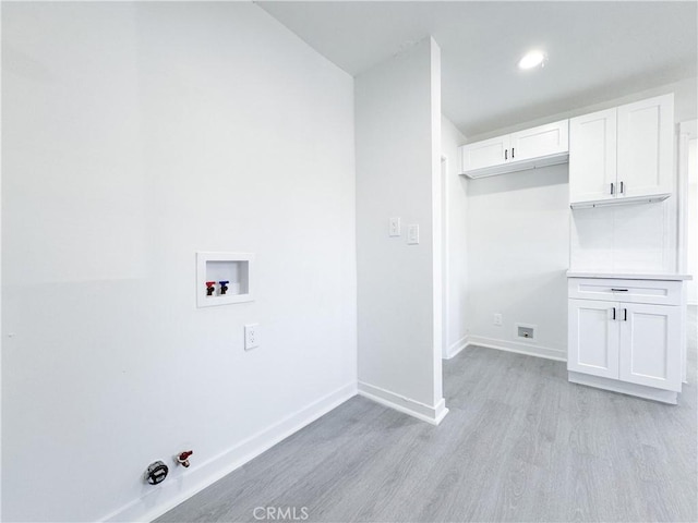 laundry room with cabinets, washer hookup, hookup for a gas dryer, and light hardwood / wood-style flooring