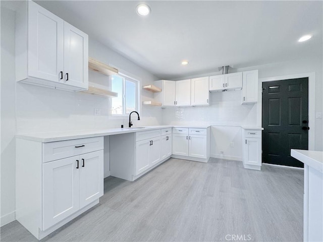 kitchen featuring light hardwood / wood-style floors, white cabinetry, sink, and decorative backsplash