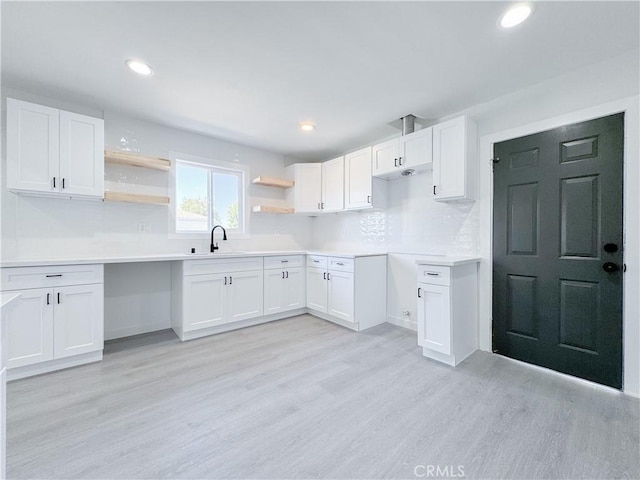 kitchen with sink, white cabinetry, backsplash, and light hardwood / wood-style flooring