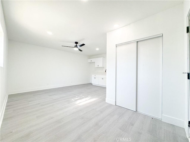 unfurnished bedroom with ceiling fan, a closet, light hardwood / wood-style flooring, and connected bathroom