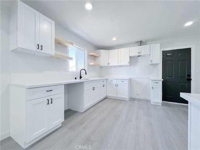 kitchen with sink, white cabinetry, light wood-type flooring, and decorative backsplash