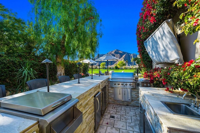 view of patio / terrace featuring an outdoor kitchen, grilling area, a mountain view, and sink