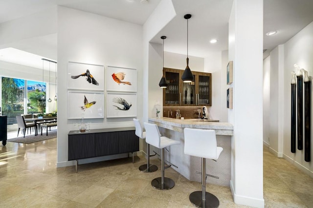 kitchen with kitchen peninsula, tasteful backsplash, hanging light fixtures, and a kitchen bar