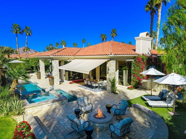 rear view of house with a fire pit and a patio