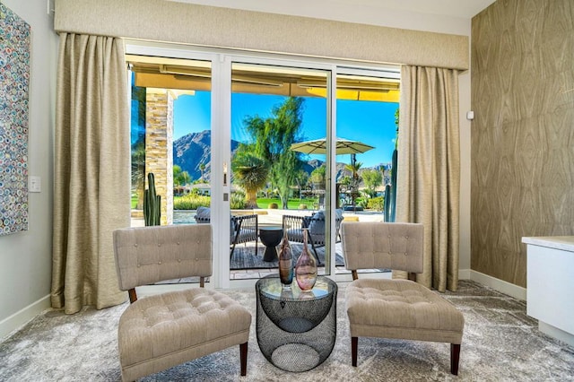 living area with a wealth of natural light, a mountain view, and carpet