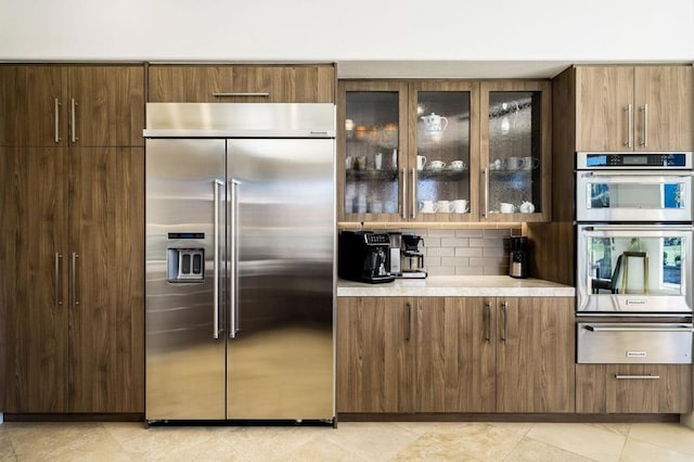 kitchen with stainless steel appliances, backsplash, and light tile patterned floors