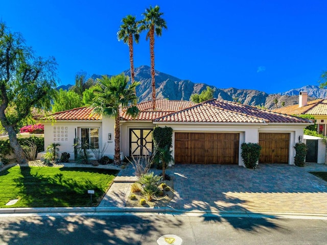 mediterranean / spanish house featuring a garage, a front lawn, and a mountain view