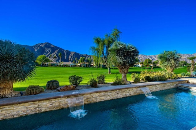 view of swimming pool featuring pool water feature, a yard, and a mountain view