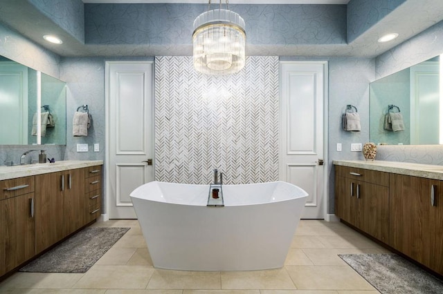 bathroom featuring a chandelier, vanity, tile patterned floors, tile walls, and a bathtub