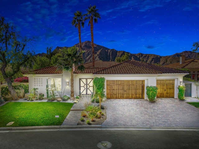 view of front facade with a yard, a garage, and a mountain view