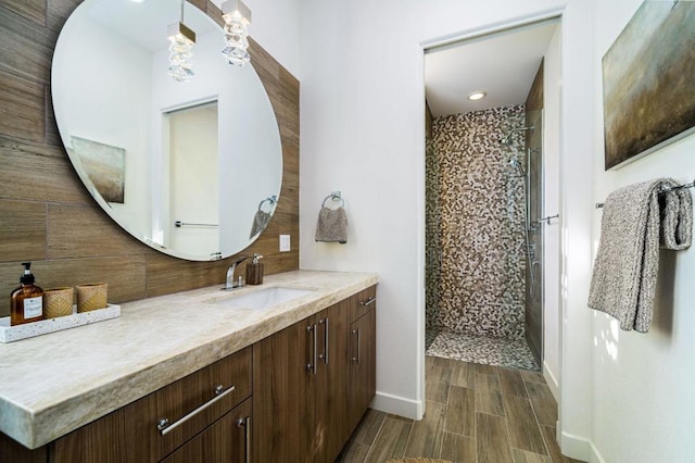 bathroom featuring a tile shower, vanity, and decorative backsplash