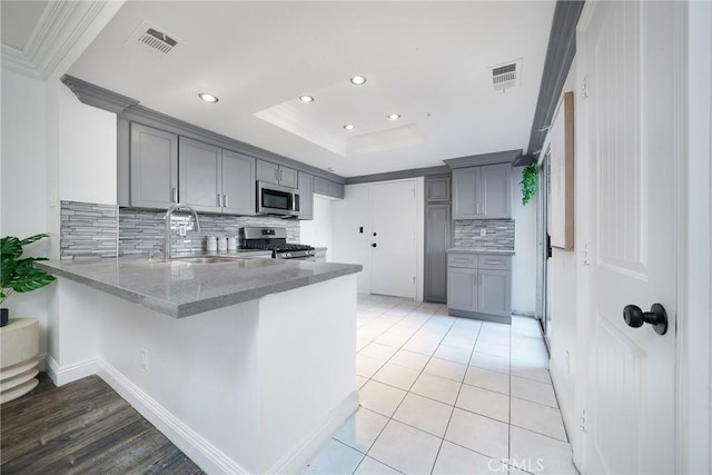 kitchen featuring stainless steel appliances, sink, gray cabinetry, and kitchen peninsula