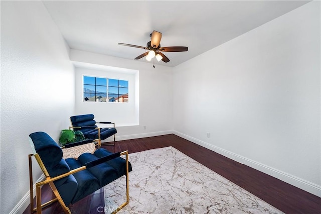 living area featuring ceiling fan and dark hardwood / wood-style flooring