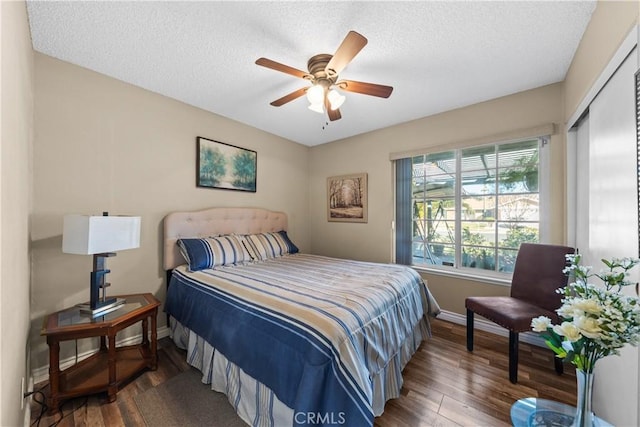 bedroom featuring a closet, dark hardwood / wood-style flooring, a textured ceiling, and ceiling fan