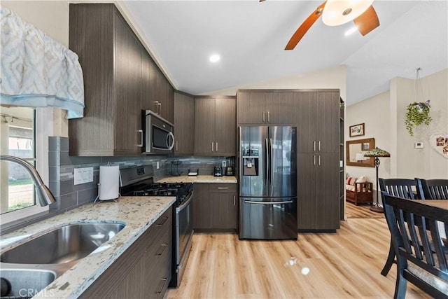 kitchen featuring sink, lofted ceiling, backsplash, dark brown cabinets, and appliances with stainless steel finishes