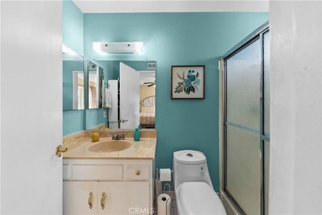 bathroom with toilet, ceiling fan, a shower with shower door, and vanity