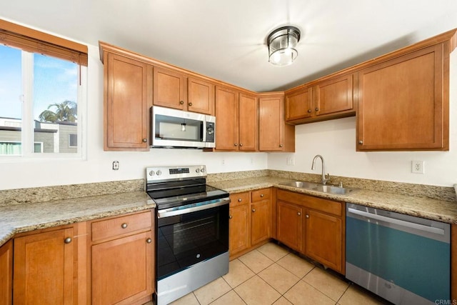 kitchen with sink, light tile patterned floors, stainless steel appliances, and light stone countertops