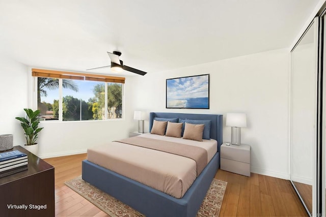 bedroom with a ceiling fan, light wood-style flooring, and baseboards