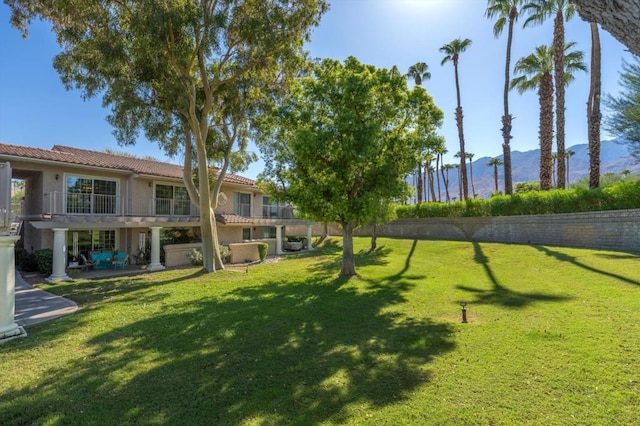 view of property's community with a patio area, a lawn, and a mountain view