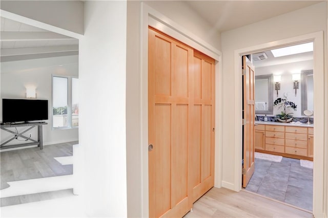 hall with light hardwood / wood-style flooring and vaulted ceiling