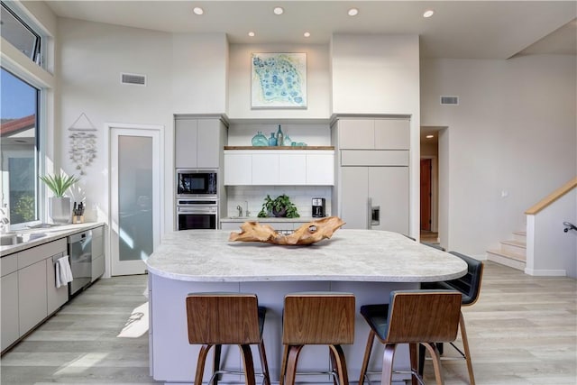 kitchen with tasteful backsplash, built in appliances, a center island, and a breakfast bar area