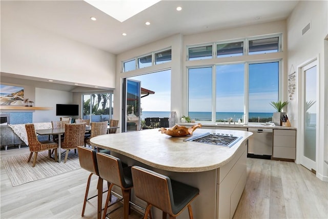 kitchen featuring light hardwood / wood-style flooring, white cabinetry, a kitchen breakfast bar, stainless steel appliances, and a center island