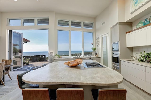 kitchen featuring sink, white cabinets, a kitchen breakfast bar, stainless steel appliances, and a water view