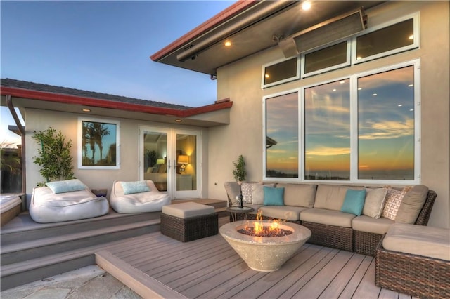 deck at dusk with an outdoor living space with a fire pit and french doors