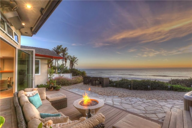 patio terrace at dusk with a water view and an outdoor living space with a fire pit