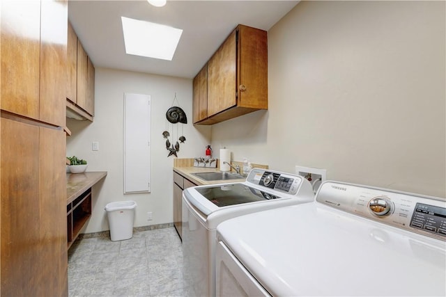 laundry room with cabinets, a skylight, sink, and washing machine and clothes dryer