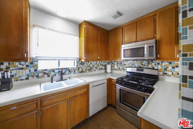 kitchen featuring sink, stainless steel appliances, dark wood-type flooring, and backsplash