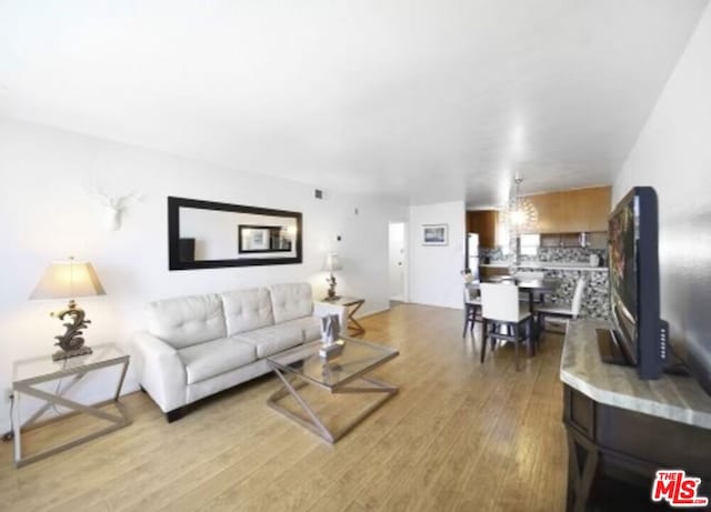 living room with a chandelier and light wood-type flooring