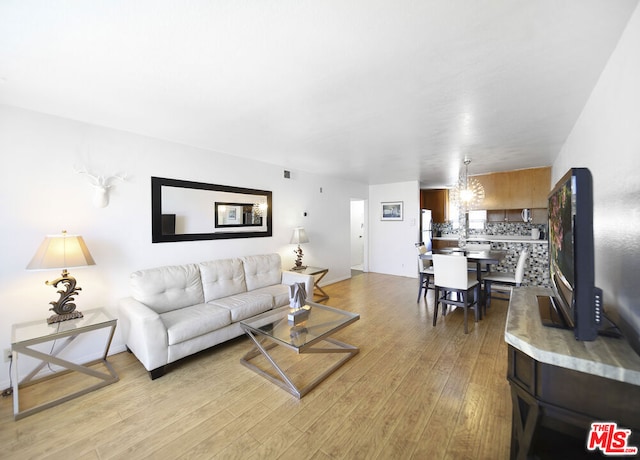 living room with an inviting chandelier and light hardwood / wood-style flooring