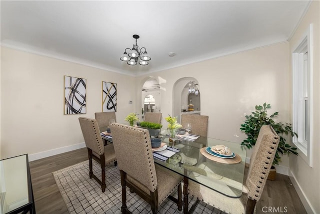 dining space featuring an inviting chandelier, crown molding, and dark hardwood / wood-style floors