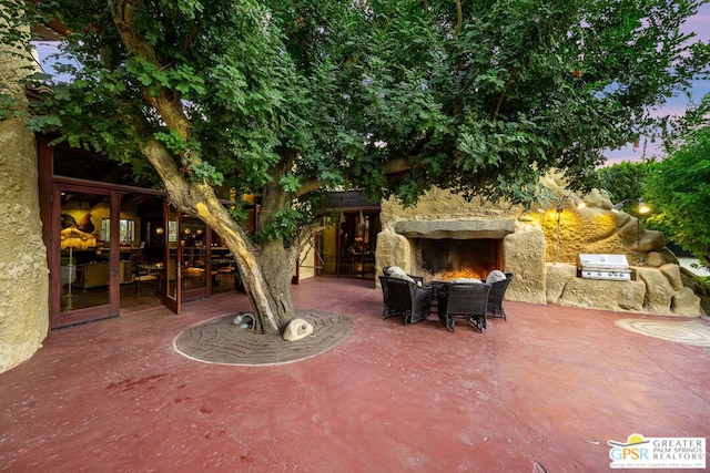 patio terrace at dusk with grilling area, an outdoor fireplace, and area for grilling