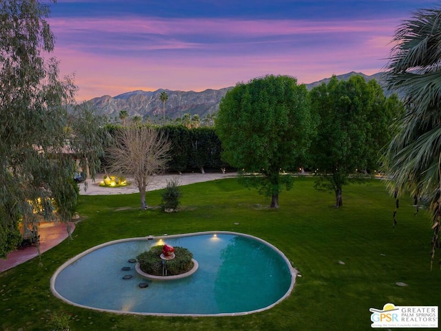 pool at dusk with a lawn and a mountain view