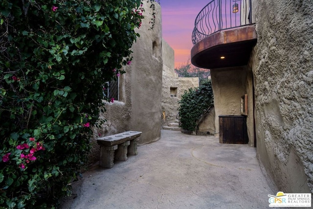 patio terrace at dusk featuring a balcony