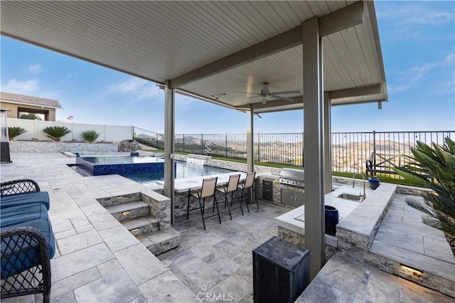 view of patio / terrace featuring a swimming pool with hot tub, area for grilling, an outdoor wet bar, and ceiling fan