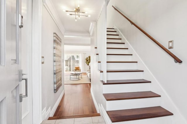 entrance foyer featuring light tile patterned floors, crown molding, and a chandelier