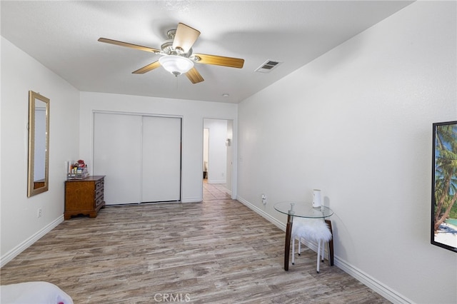 bedroom featuring ceiling fan, light hardwood / wood-style flooring, and a closet