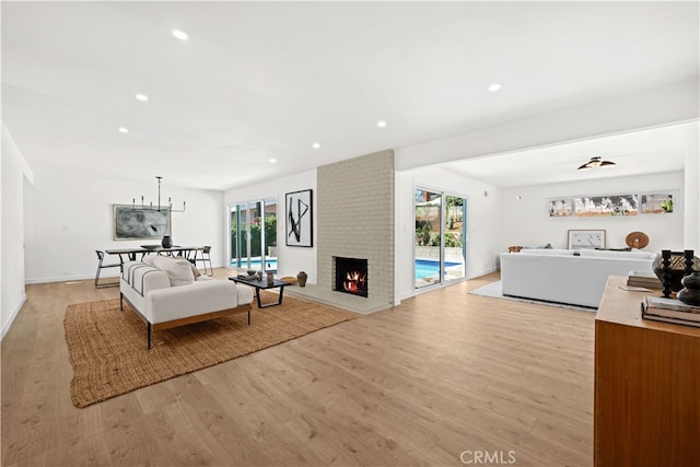 living room featuring light hardwood / wood-style flooring, a brick fireplace, and plenty of natural light