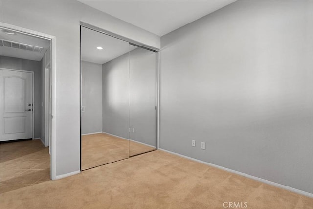 unfurnished bedroom with a closet and light colored carpet