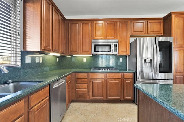 kitchen featuring stainless steel appliances, sink, dark stone countertops, light tile patterned floors, and decorative backsplash