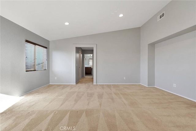 unfurnished room featuring light colored carpet and vaulted ceiling