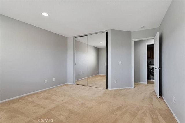 unfurnished bedroom featuring light colored carpet, washer / dryer, and a closet