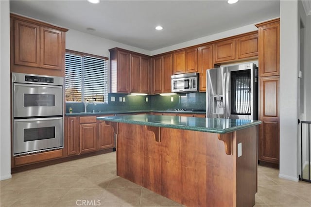 kitchen with a breakfast bar, light tile patterned floors, a kitchen island, appliances with stainless steel finishes, and sink